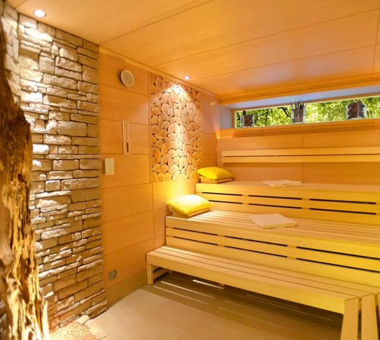 Sauna mit indirekter Beleuchtung, Holzbänke in mehreren Ebenen, dekorative Natursteinwand.