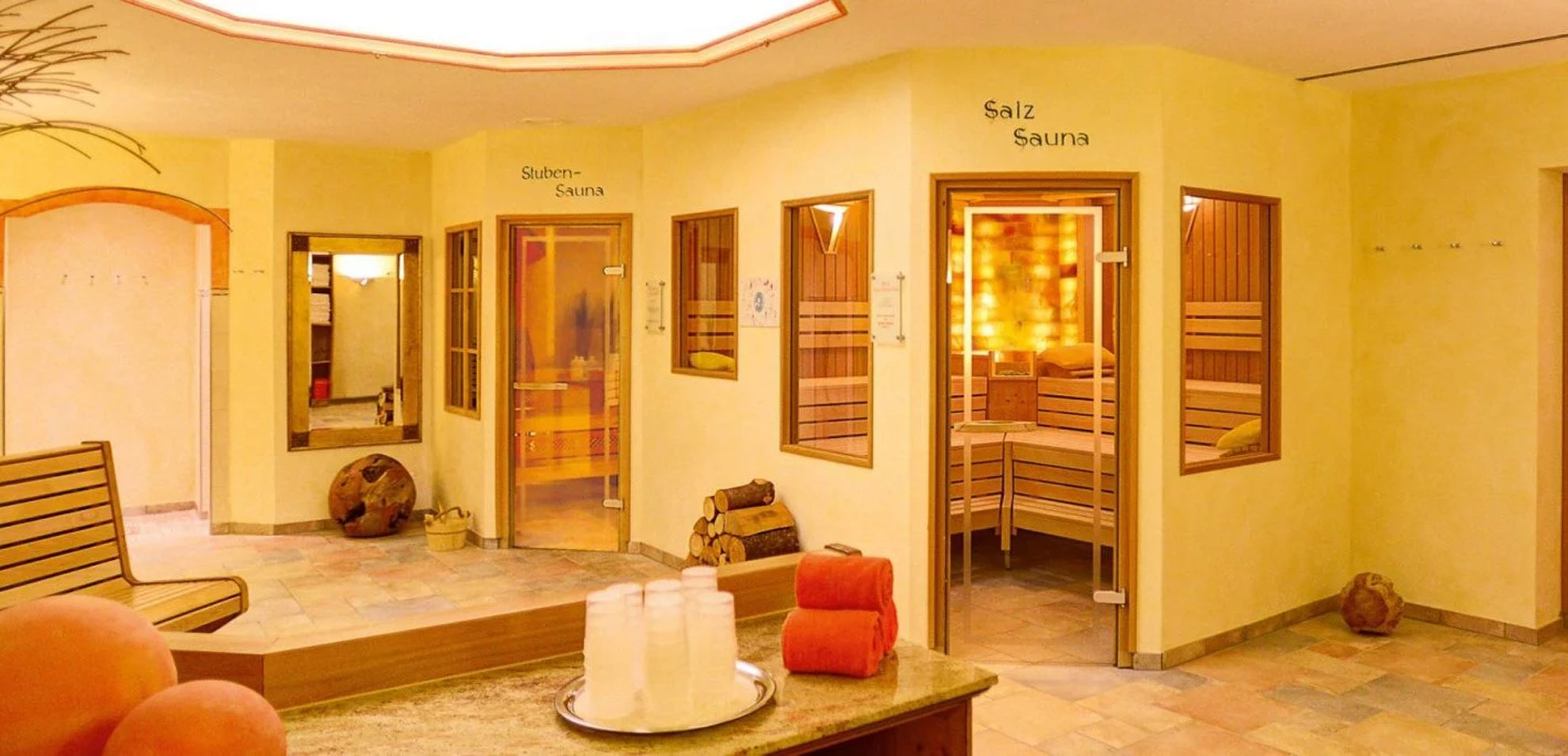 Flur vor dem Spa mit zwei Saunakabinen, heller Fliesenboden, weiße Handtücher und dekorative Vasen.