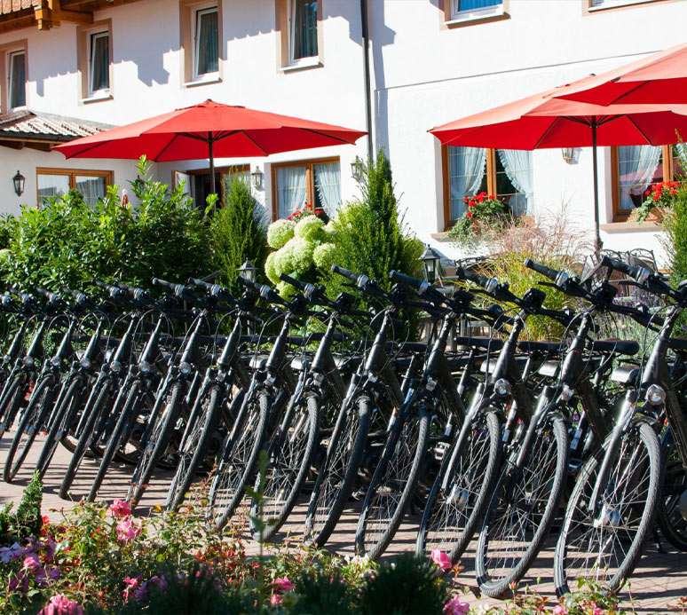 Fahrradverleih mit mehreren E-Bikes in Reihung vor dem Hoteleingang.