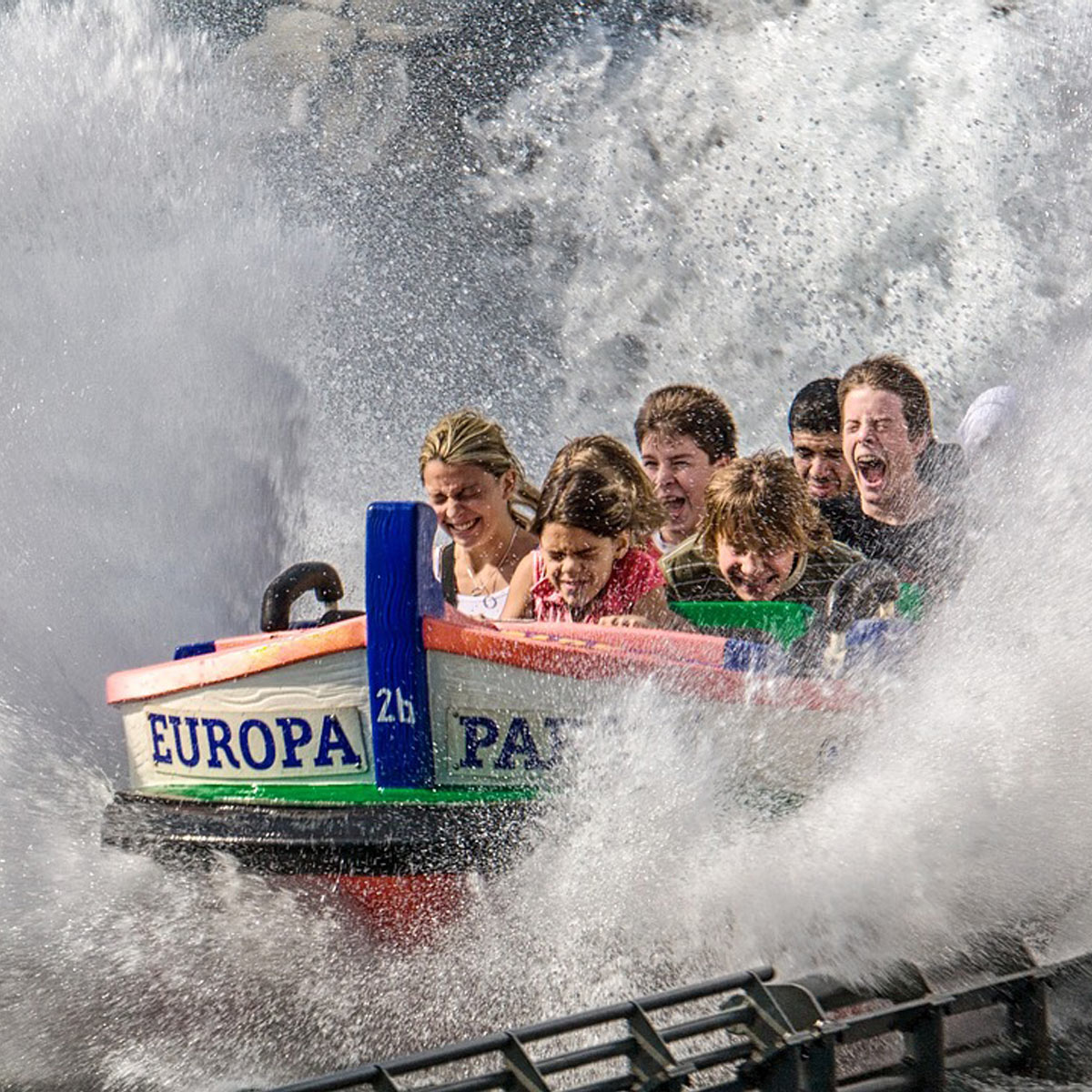 Boot der Wasserattraktion „Fjord Rafting“ im Europa-Park mit vier lachenden Personen, spritzendem Wasser und Logo gut lesbar.