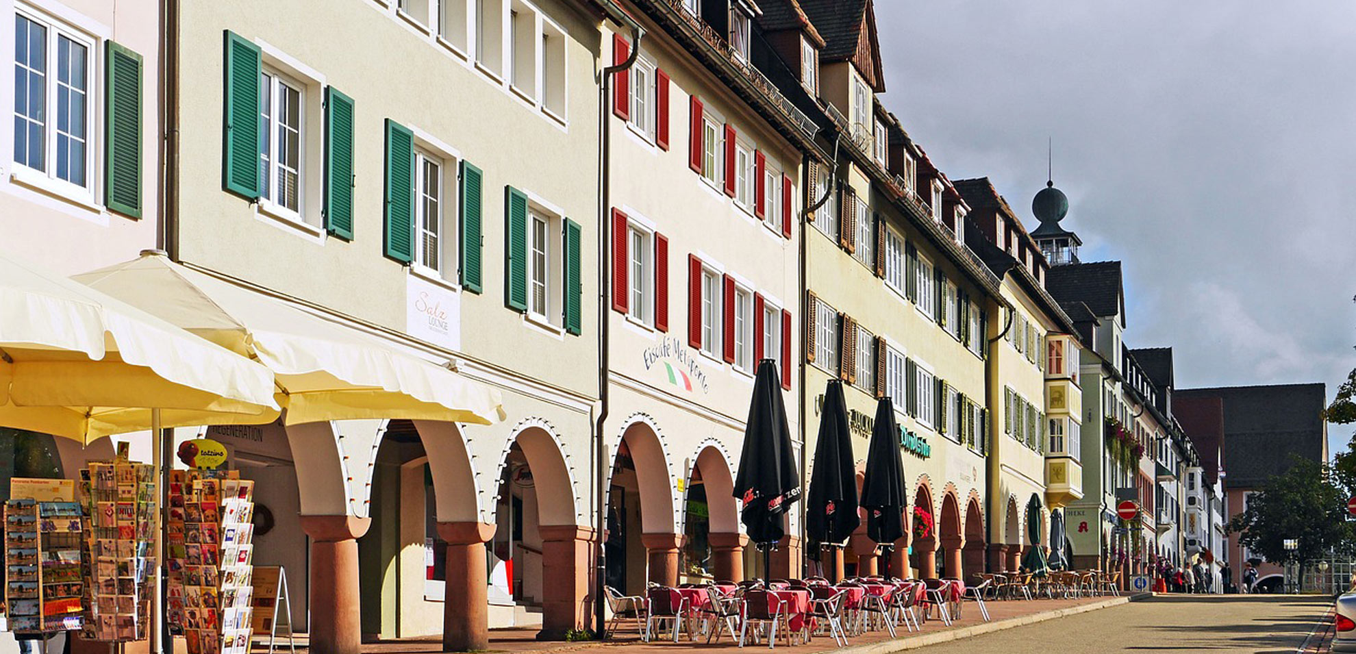 Arkadenstraße in Freudenstadt mit Geschäften und Cafés unter grün-roten Fensterläden.