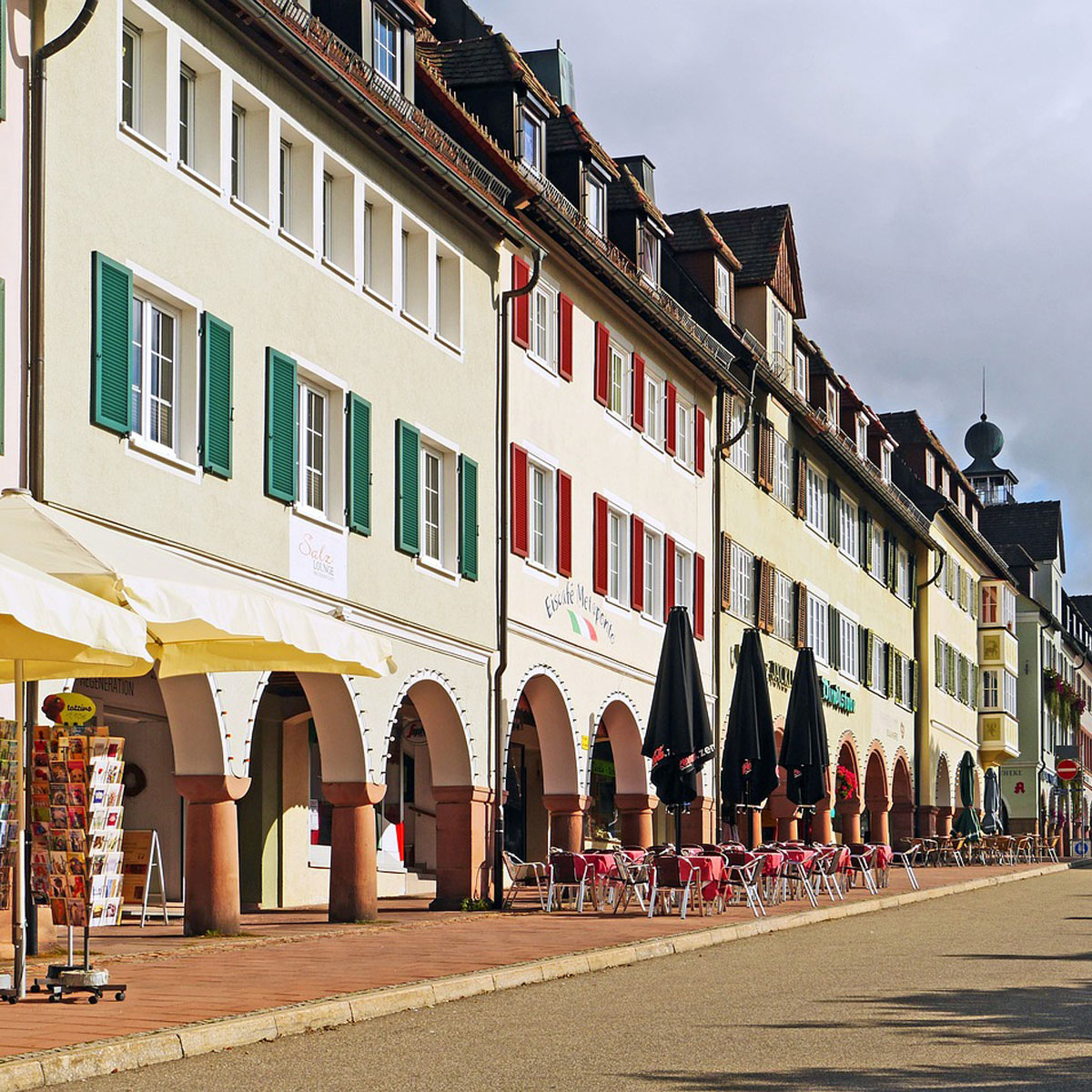 Arkadenstraße in Freudenstadt mit Geschäften und Cafés unter grün-roten Fensterläden.