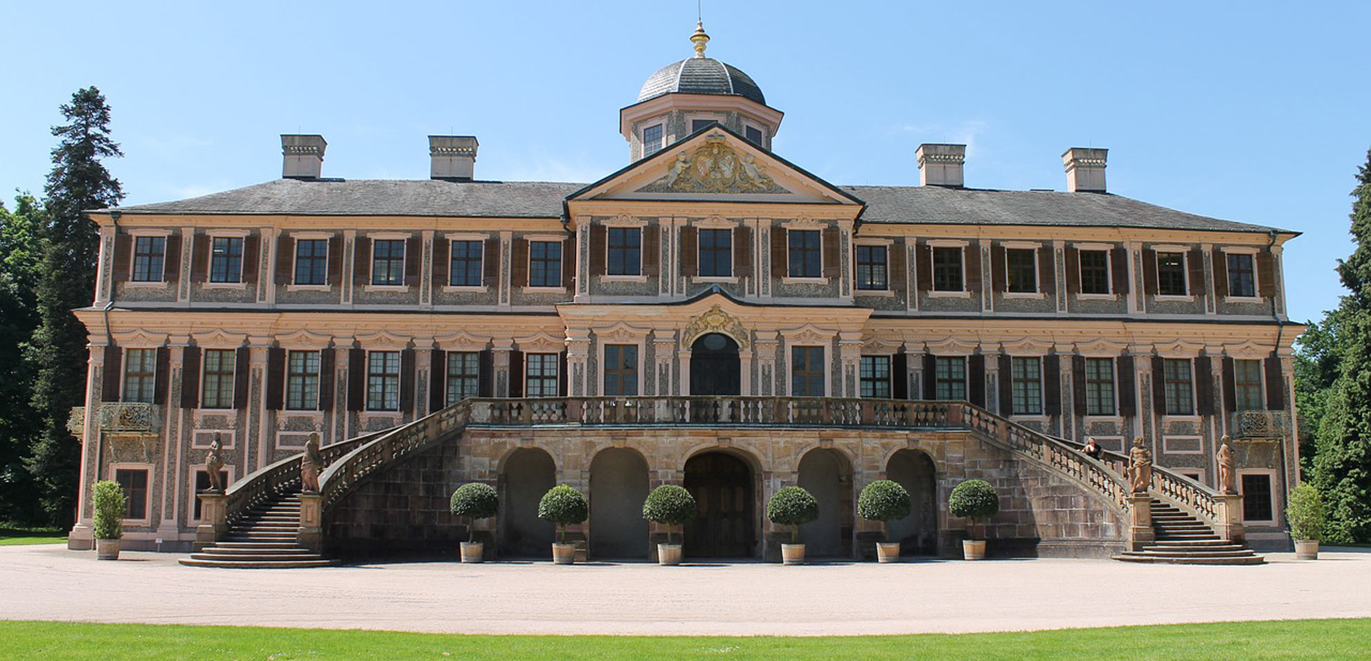 Historisches Schlossgebäude in Rastatt mit Rasenfläche davor und Säulenarchitektur.