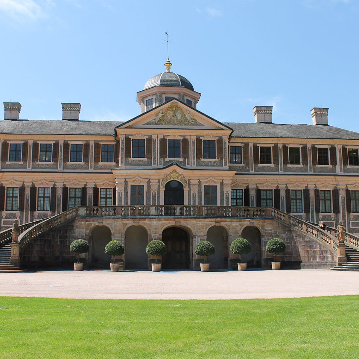 Historisches Schlossgebäude in Rastatt mit Rasenfläche davor und Säulenarchitektur.