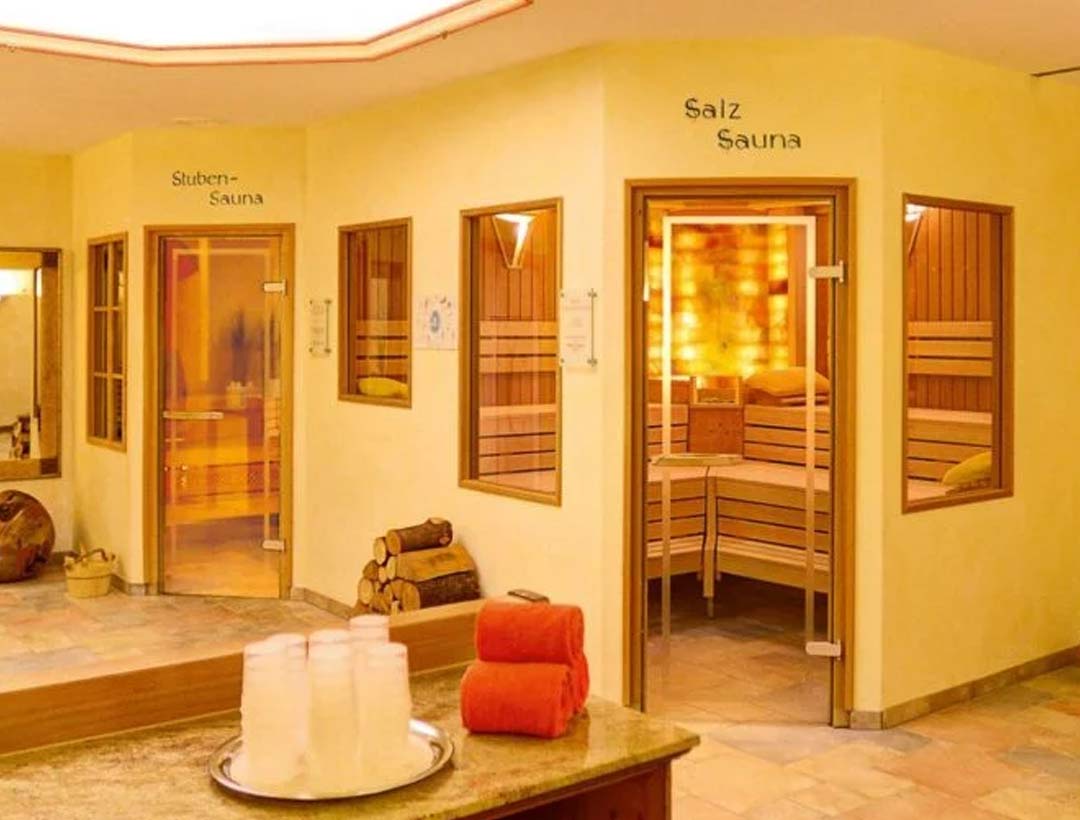 Spa-Bereich des Hotels mit zwei separaten Saunakabinen, gefliestem Boden, dekorativer Wandnische und bereitgelegten Handtüchern.