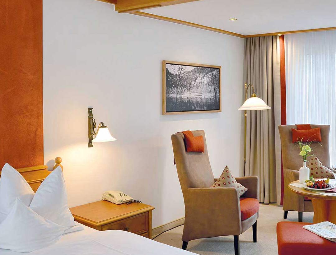 Doppelbett-Zimmer mit roten Vorhängen, Holzmöbeln und Fenster mit Ausblick, dekoratives Bild an der Wand.