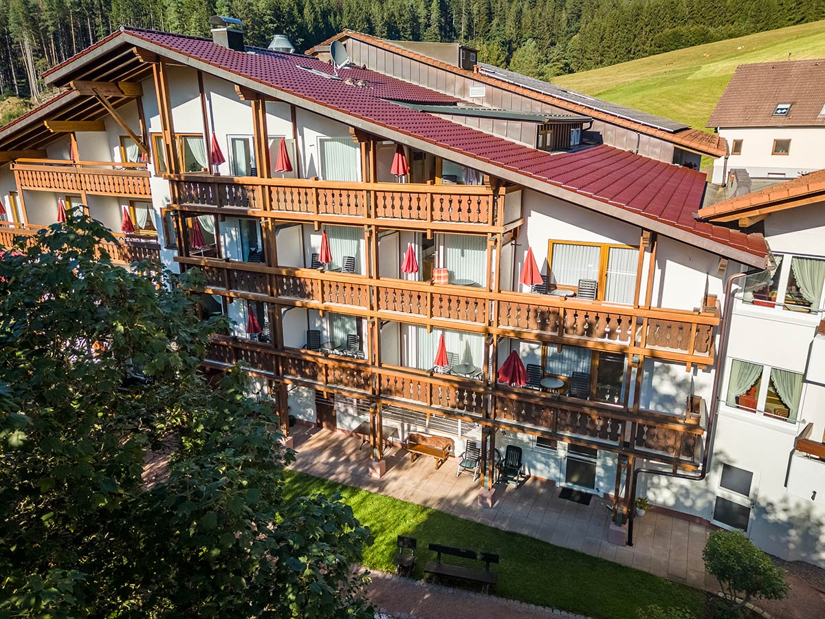 Ansicht des mehrstöckigen Hoteltrakts mit umlaufenden Balkonen, Blick auf Sonnenliegen und Sonnenschirme.