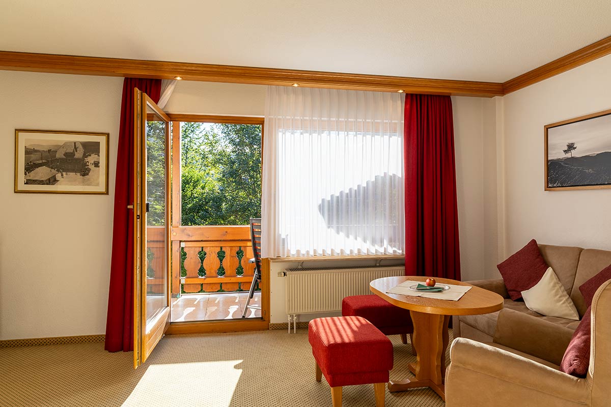 Wohnbereich mit gepolsterten Sofas in Creme, Couchtisch und Fenster mit geöffnetem Vorhang.