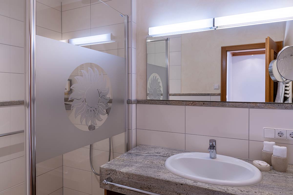 Waschplatz mit rundem Waschbecken, großem Spiegel und Licht von oben, moderne weiße Fliesen.