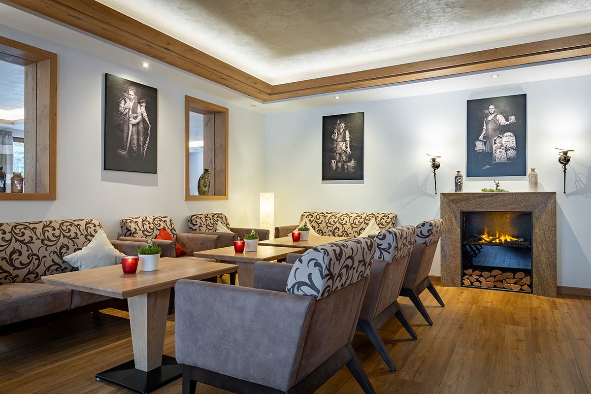 Mehrere Sofas in Grau und Beige um Couchtische gruppiert, Holzdecke mit Spotlights, Wände mit Gemälden.