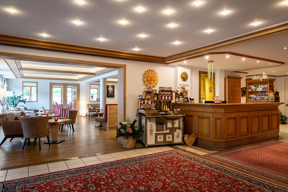 Hotellobby mit Rezeptionstresen aus Holz, orientalischem Teppich, Wanduhr und dekorativem Eingangsbereich.