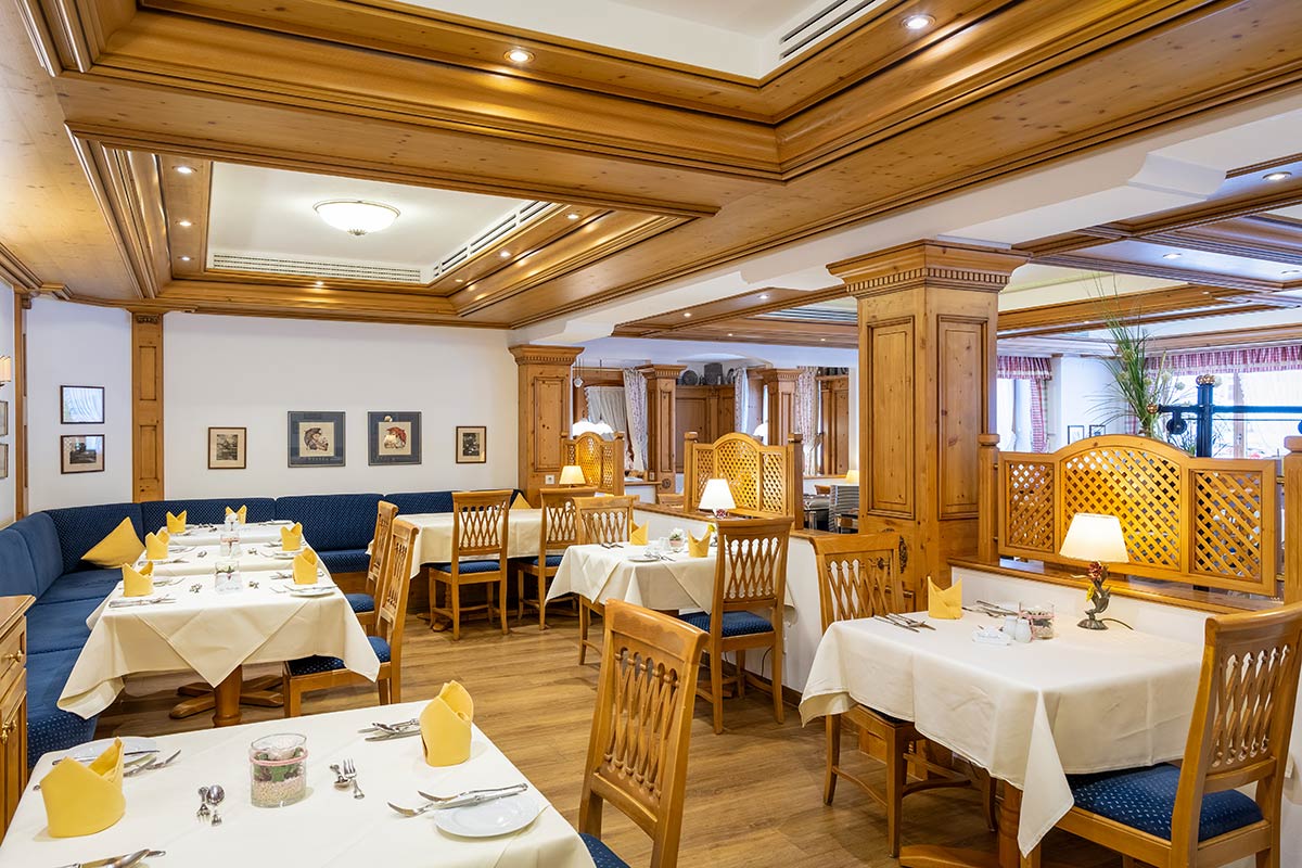 Frühstücksraum mit hellen Holzmöbeln, gedeckten Tischen und Fensterblick nach draußen.