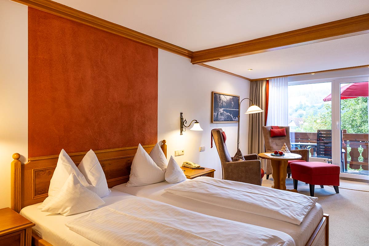 Schlafzimmer mit Doppelbett, zwei Kissen, Leselampen, Holzmöbeln und Tageslicht von rechts.