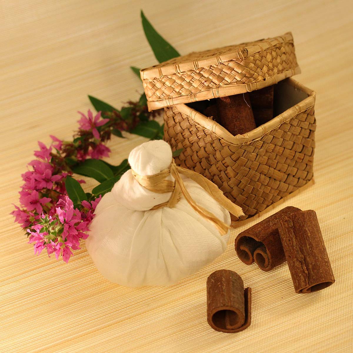 Wellness-Arrangement auf Holzplatte mit Kräuterstempel, Naturmaterialien und Blüten.